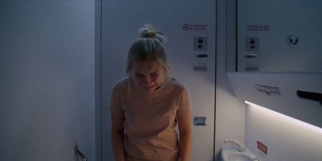 a woman is standing in a bathroom looking at the mirror