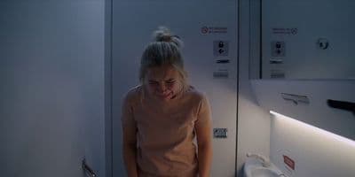 a woman is standing in a bathroom looking at the mirror