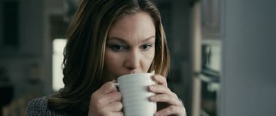 a woman drinking a cup of coffee in a kitchen