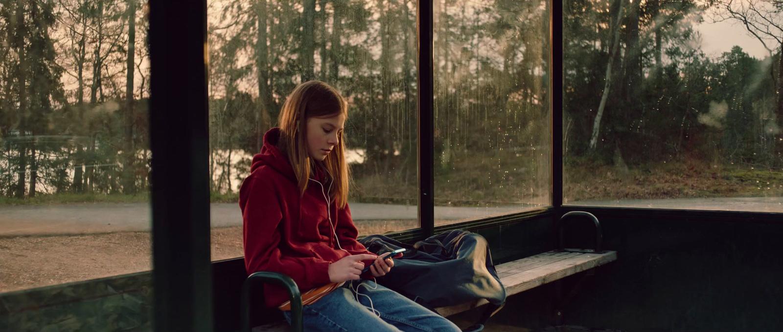 a girl sitting on a bench with a backpack