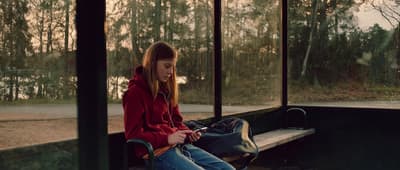 a girl sitting on a bench with a backpack
