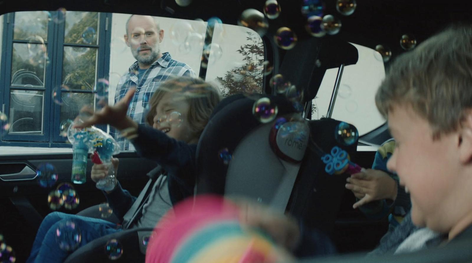 a group of children playing with bubbles in the back seat of a car