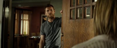 a man standing in front of a door looking at a woman