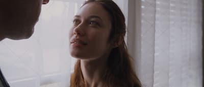 a man and woman looking at each other in a window