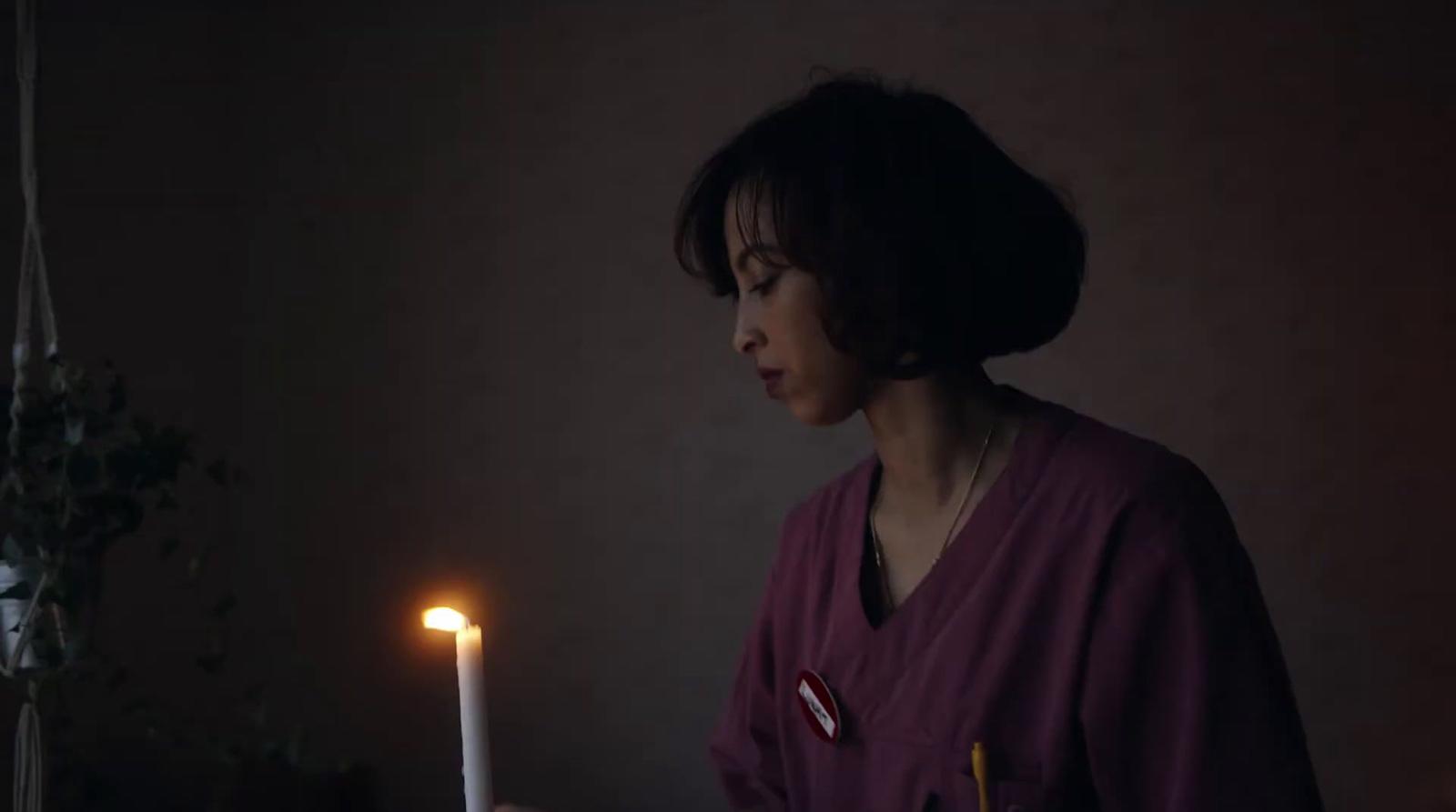 a woman is holding a candle in the dark