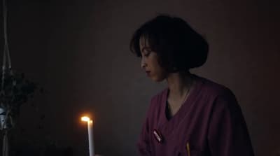 a woman is holding a candle in the dark