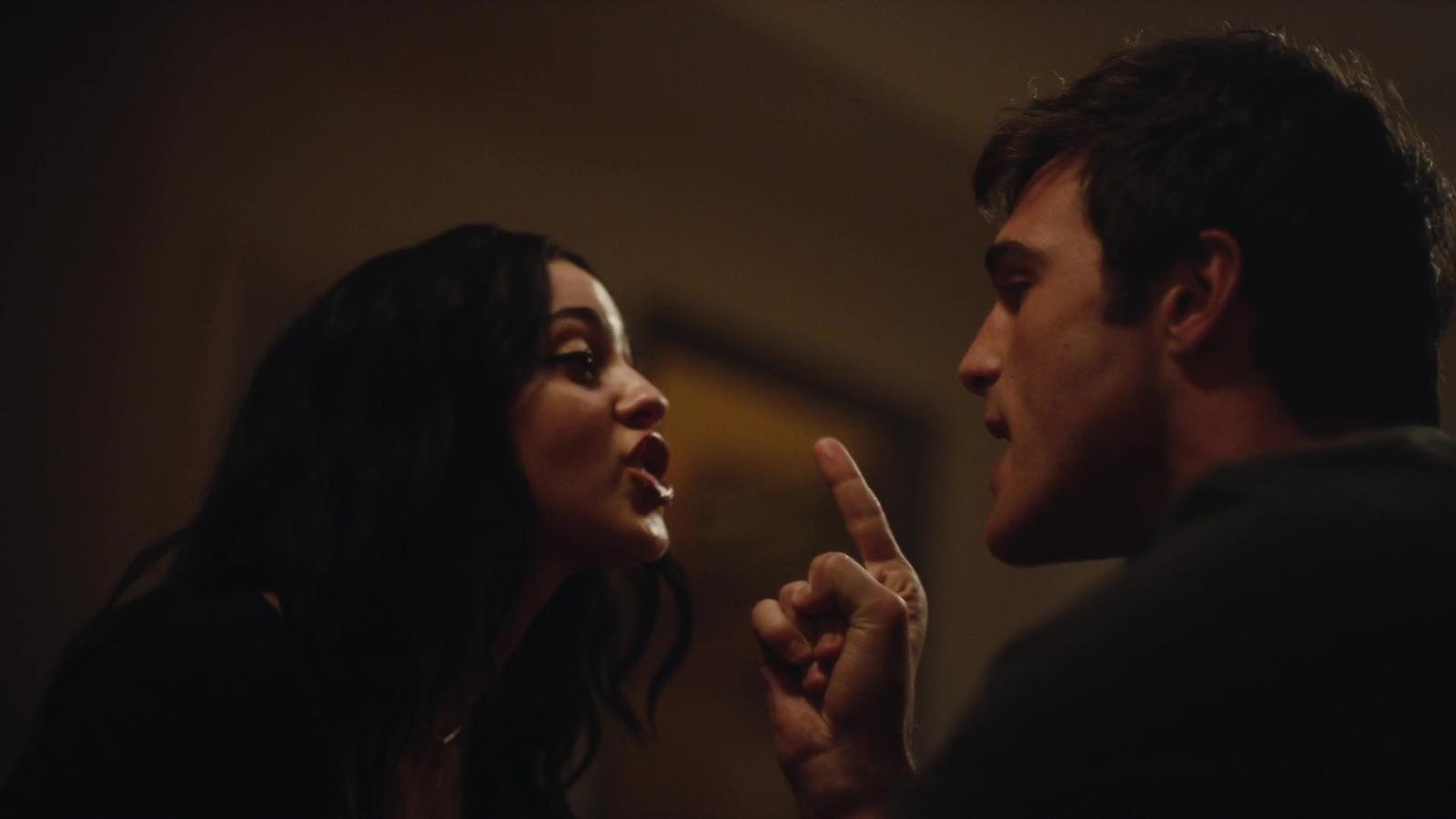 a man and a woman looking at each other in a dark room