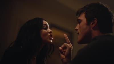 a man and a woman looking at each other in a dark room