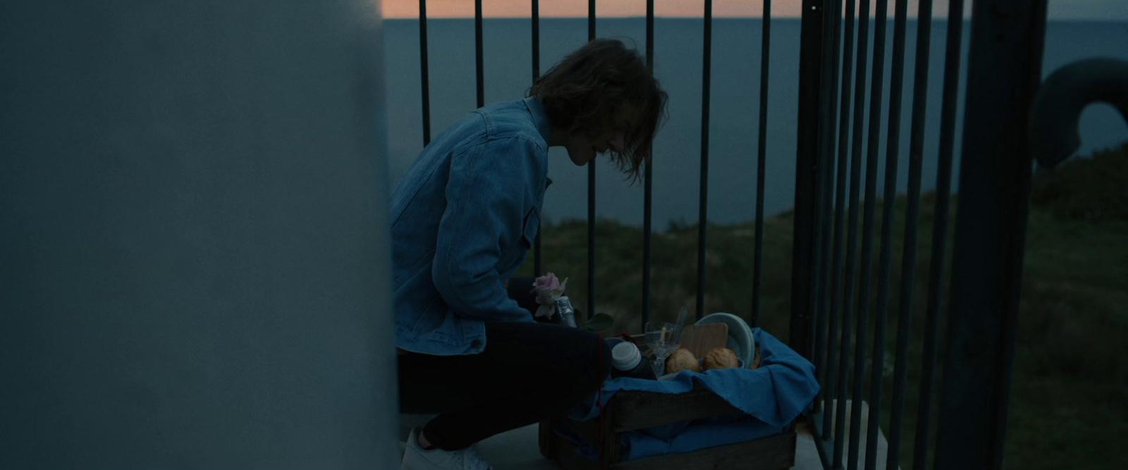 a woman sitting on a railing looking at the ocean