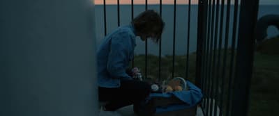 a woman sitting on a railing looking at the ocean