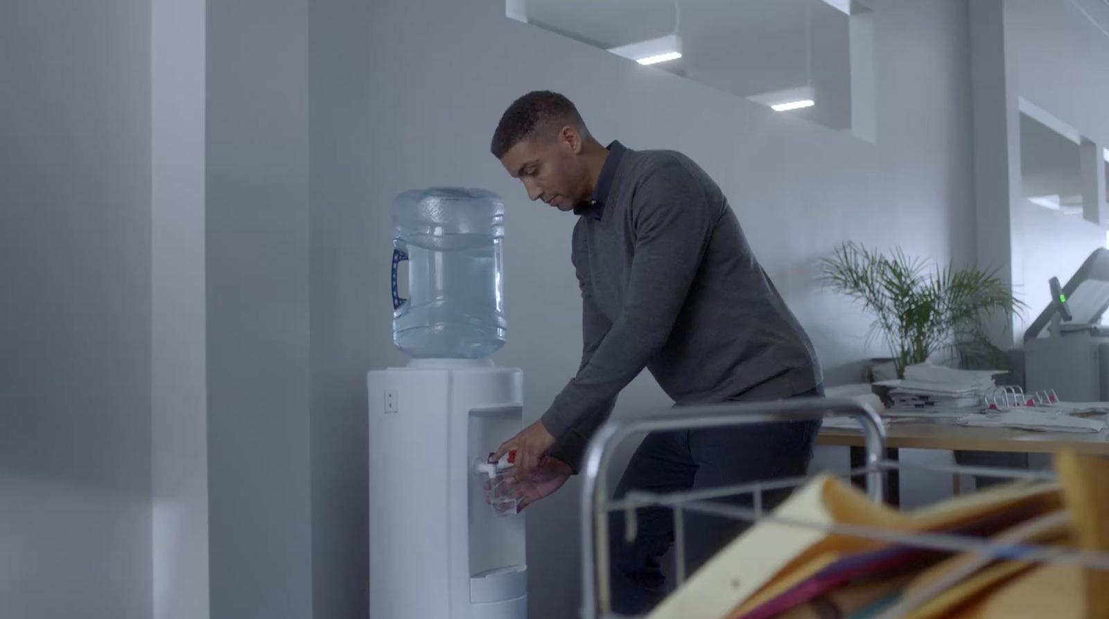 a man filling a water dispenser in an office