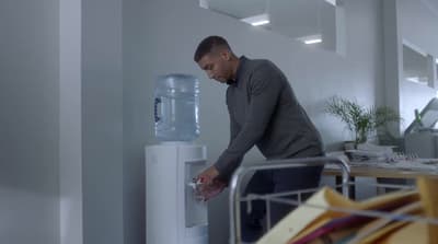a man filling a water dispenser in an office