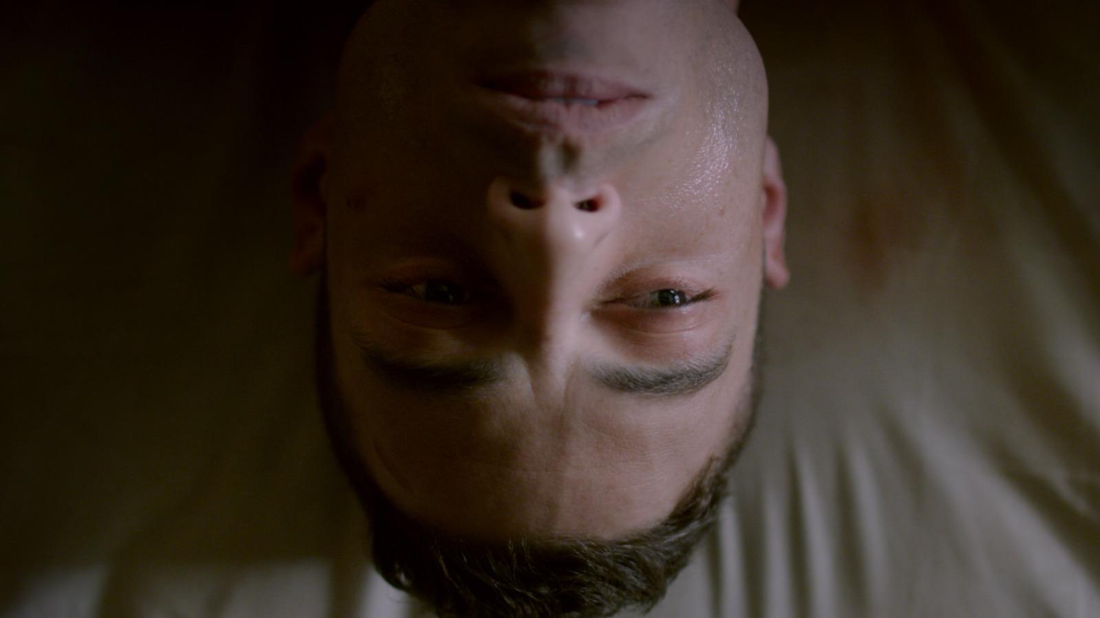 a man laying on a bed with his head in the air