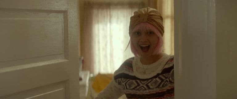 a woman with pink hair standing in a doorway