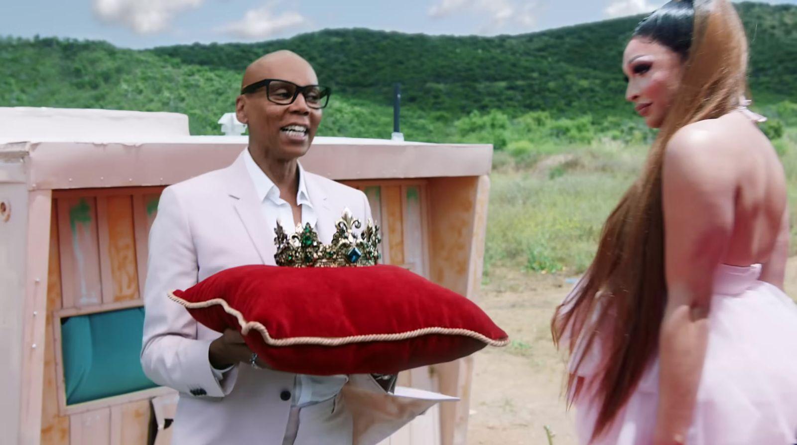 a man in a white suit holding a red pillow