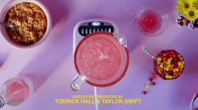a pink drink with a spoon in it next to a bowl of cereal