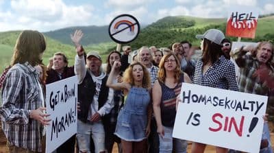 a group of people holding signs in front of a hill