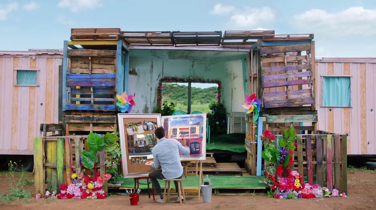 a man sitting at a easel in front of a painting