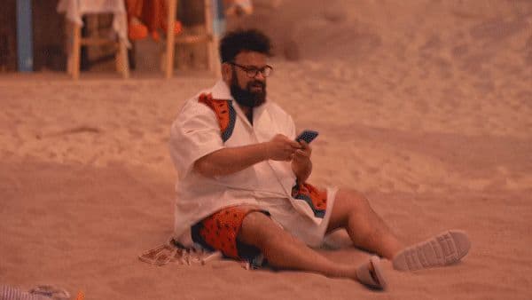 a man sitting in the sand looking at his cell phone