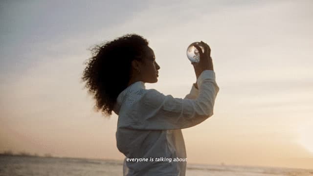 a woman standing on a beach holding a glass ball