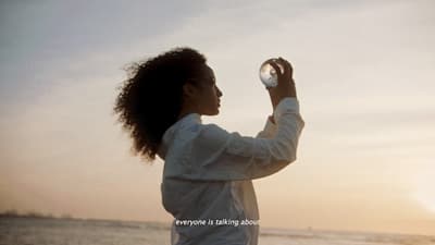 a woman standing on a beach holding a glass ball