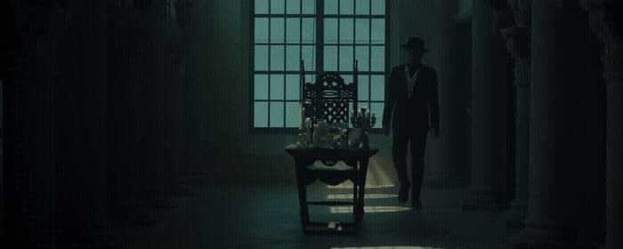 a man standing in a dark room next to a table
