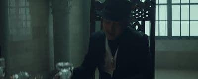a man in a suit and hat standing in a room