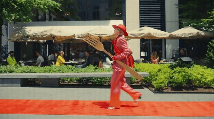 a man in a red suit carrying a wooden paddle