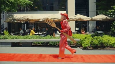 a man in a red suit carrying a wooden paddle