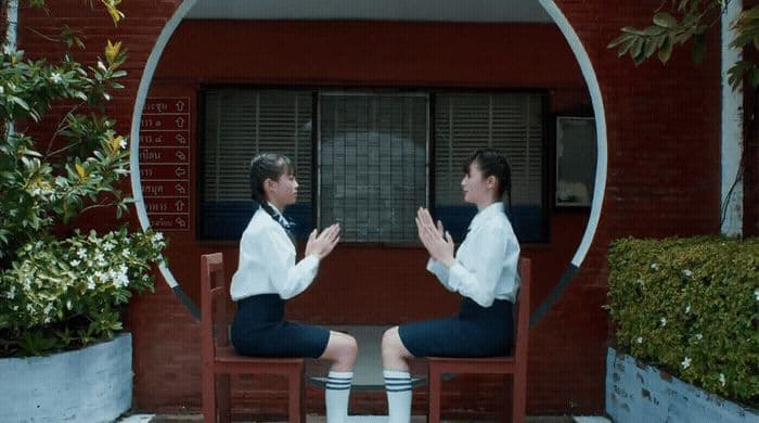 two women sitting on chairs in front of a building
