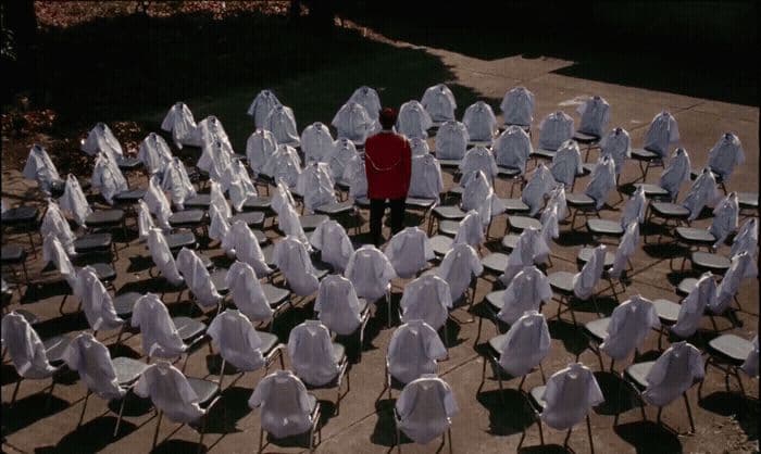 a man standing in front of a large group of white chairs