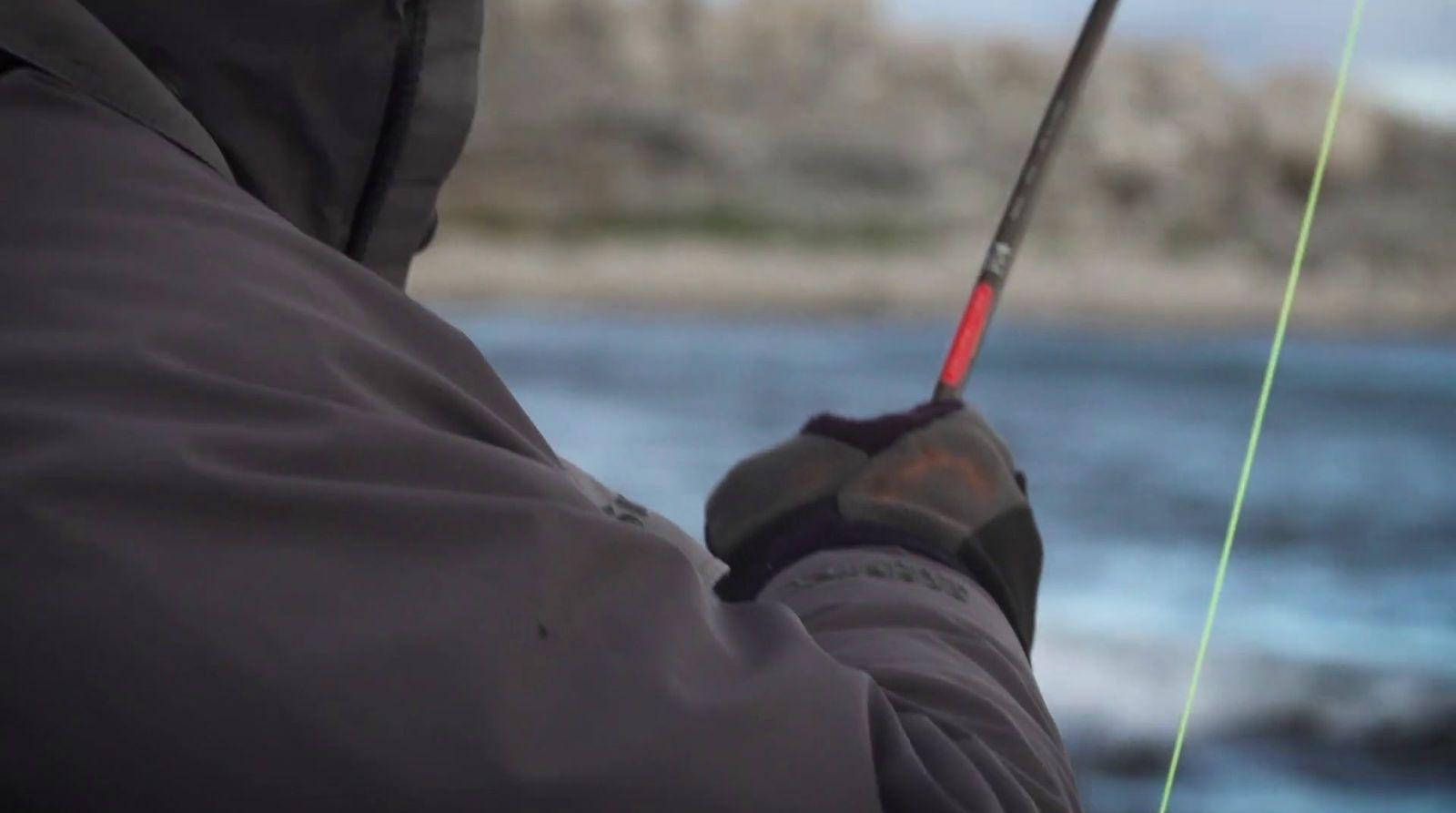 a man holding a fishing rod while standing next to a body of water