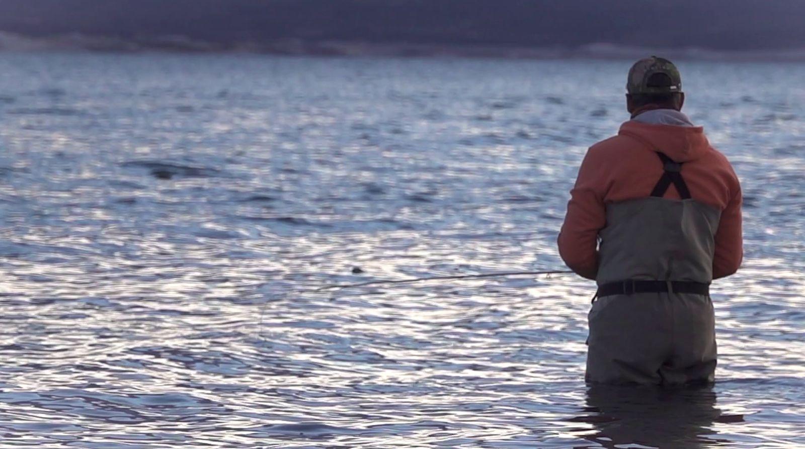 a man standing in the water while fishing