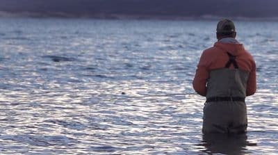 a man standing in the water while fishing