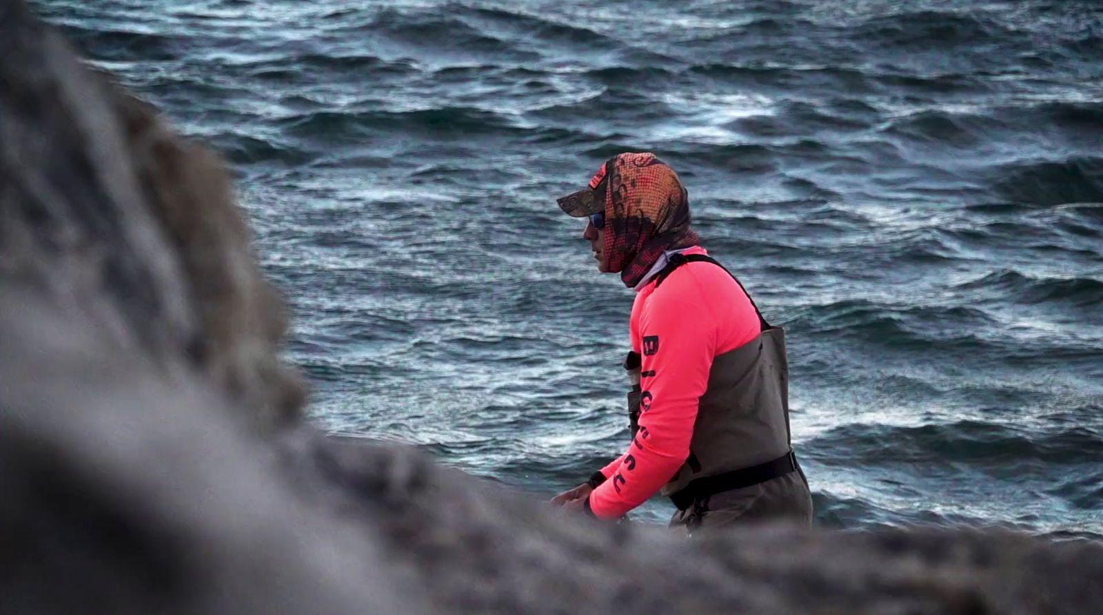 a man standing on top of a rocky cliff next to the ocean