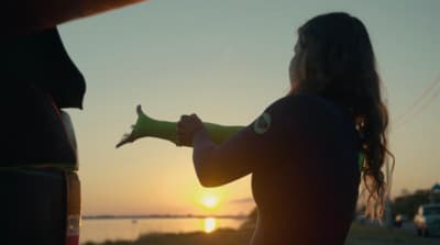 a woman in a wet suit holding a banana