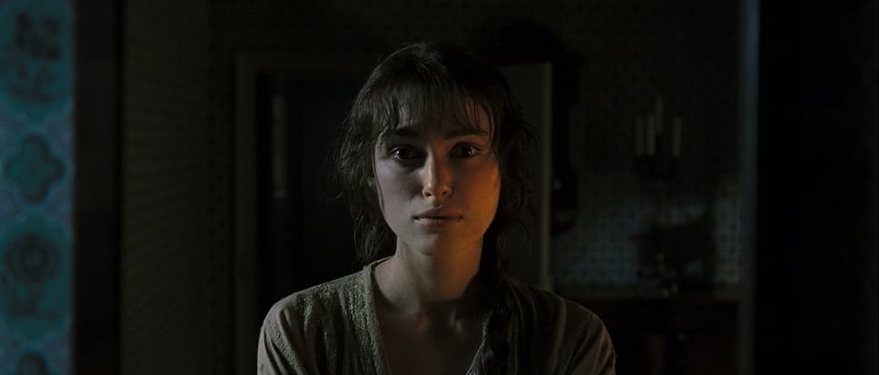 a woman standing in a dark room looking at the camera
