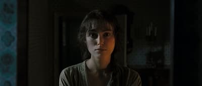 a woman standing in a dark room looking at the camera