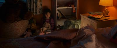 a little girl sitting on a bed with stuffed animals