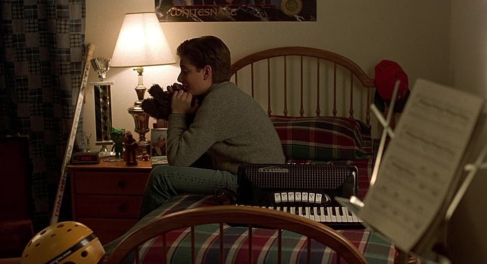 a boy sitting on a bed holding a teddy bear