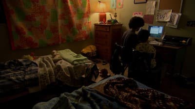 a couple of people standing in a bedroom next to a bed