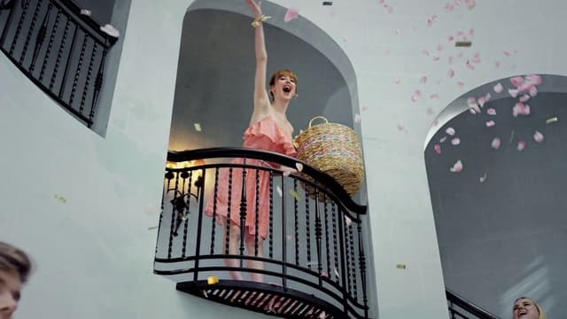 a woman in a pink dress standing on a balcony
