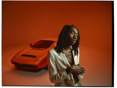 a man with dreadlocks standing next to a car