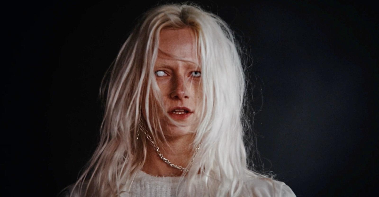 a woman with white hair and a chain around her neck