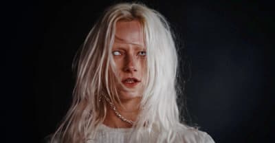 a woman with white hair and a chain around her neck