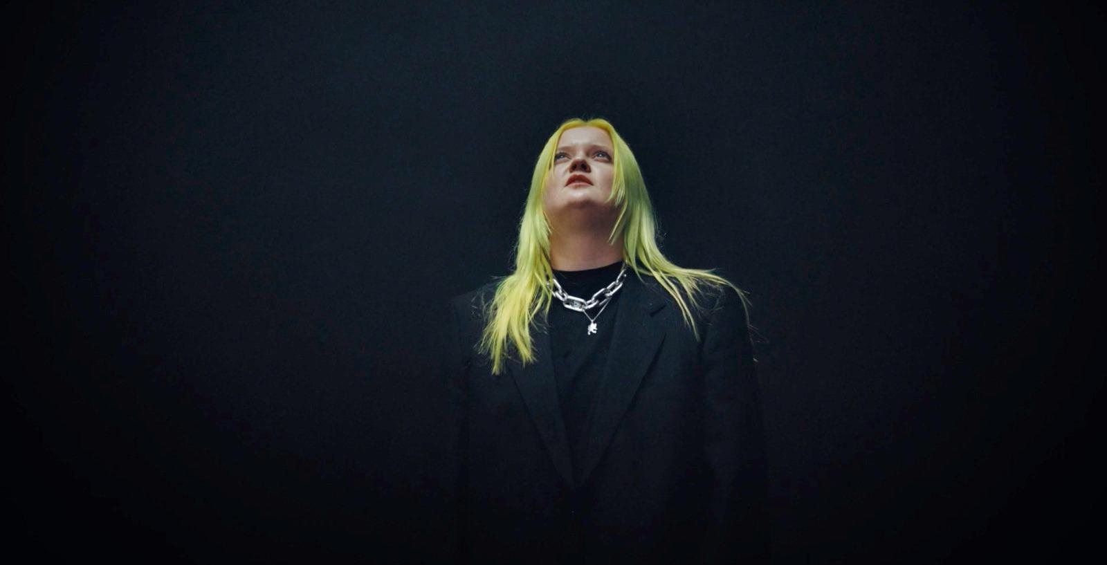 a woman with long blonde hair standing in the dark