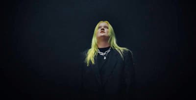a woman with long blonde hair standing in the dark