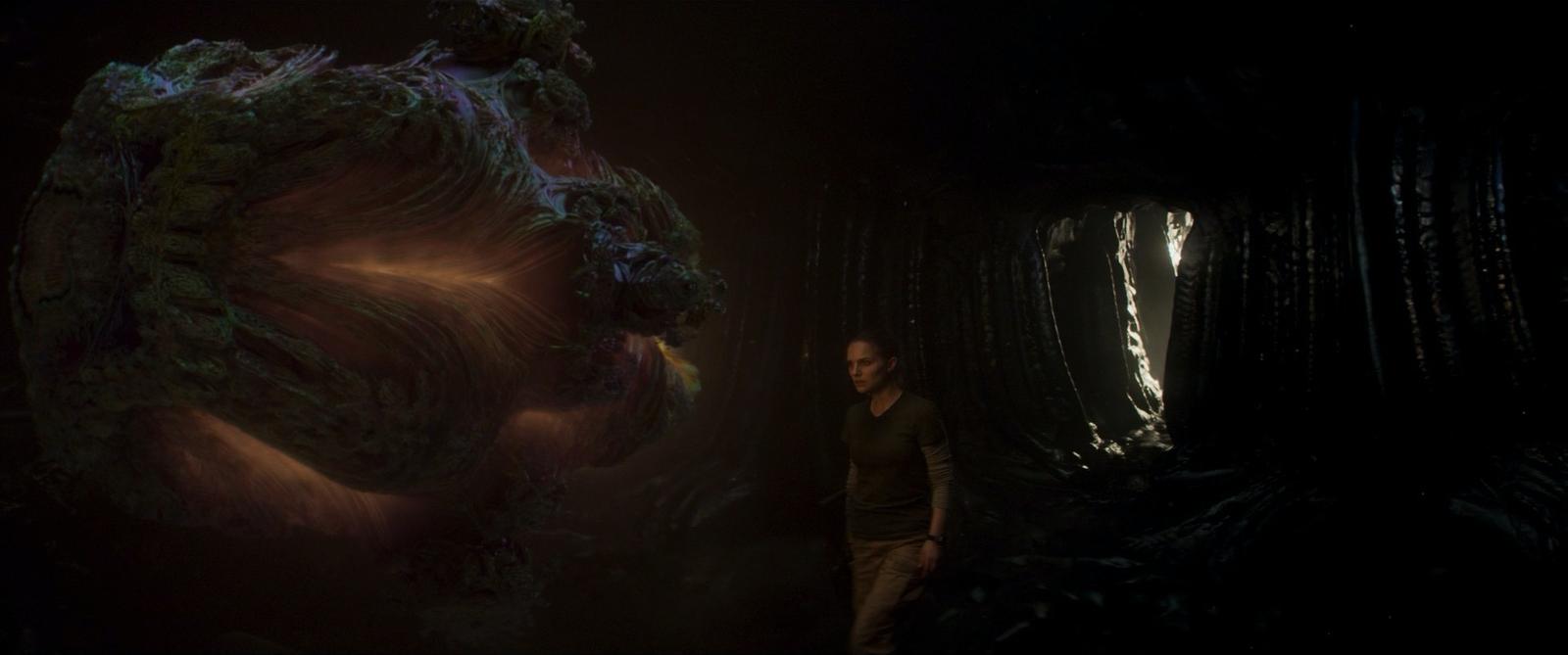 a woman standing in a dark room next to a giant object