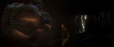 a woman standing in a dark room next to a giant object
