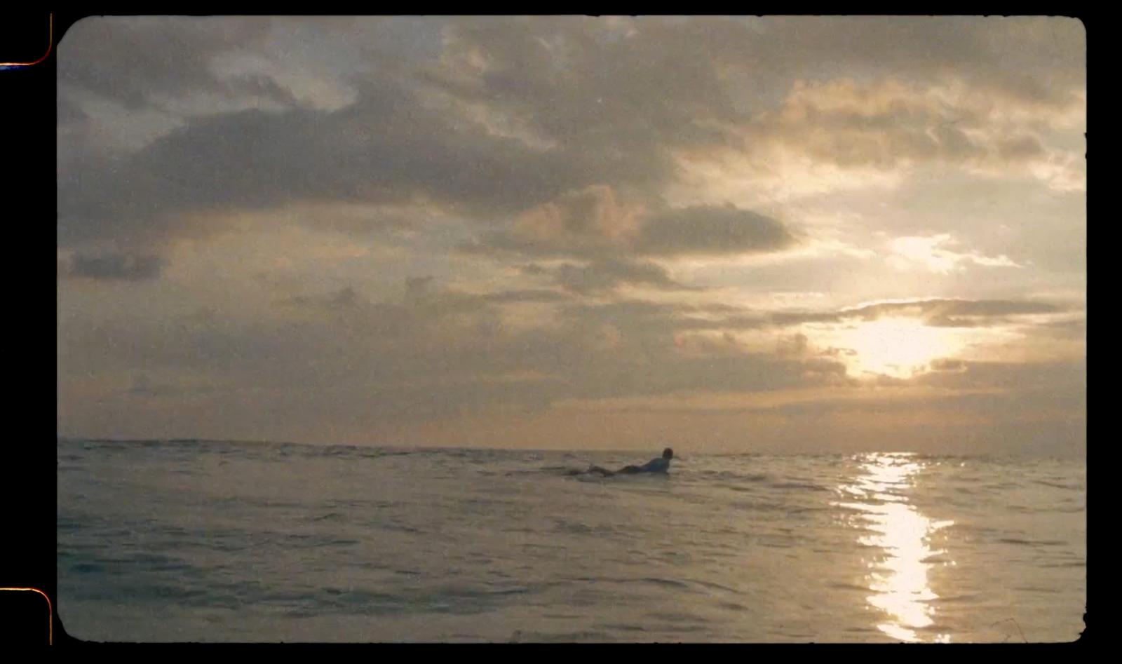a person riding a surfboard in the ocean at sunset
